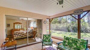 Una habitación acogedora con una cama, una mesa de madera, un sofá verde con estampado y un ventanal que ofrece vistas al exterior.