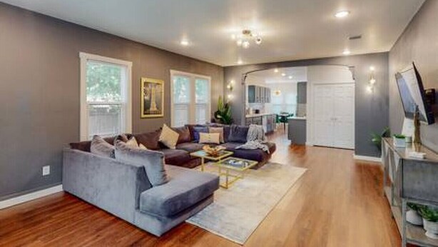 A modern living room with a grey sofa, a coffee table, and a TV on a stand. - Prohibition Vibes | LUX | Mini Golf | Walk to AT&T (Arlington)