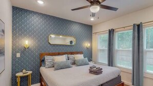 A bedroom with a bed, a ceiling fan, a nightstand, a mirror, and a window with curtains. - Prohibition Vibes | LUX | Mini Golf | Walk to AT&T (Arlington)