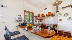 A kitchen with a wooden countertop, a microwave, a toaster, a sink, and a window.