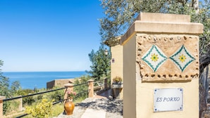 A coastal pathway with a sign reading 'ES PORXO,' leading to a scenic view of the sea.