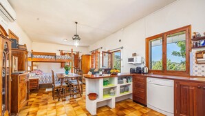 A kitchen with a wooden floor, a dining area with a table and chairs, a built-in oven, and a window with a view.