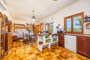 A kitchen with a wooden floor, a dining area with a table and chairs, a built-in oven, and a window with a view.