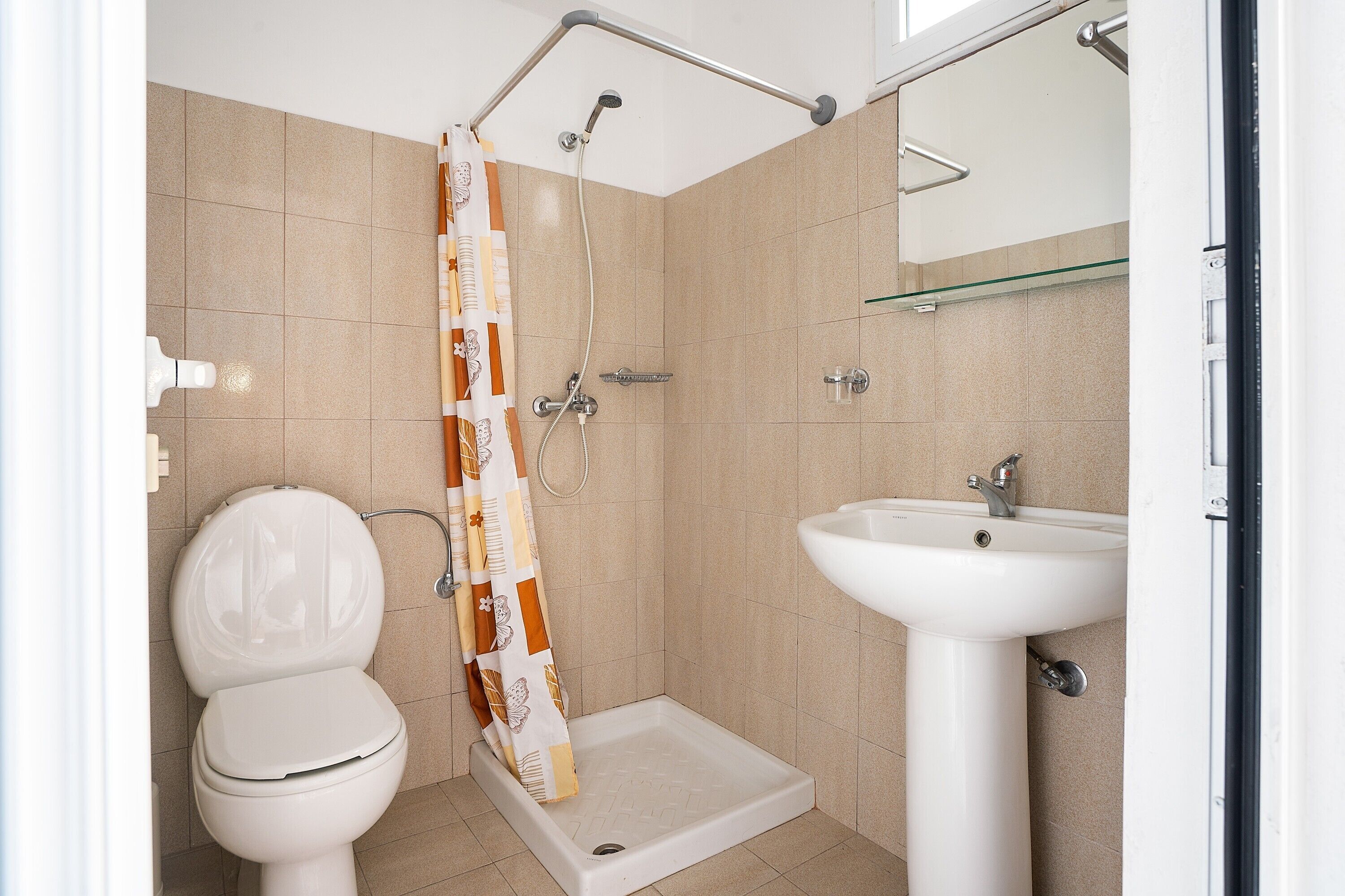 Een badkamer met douche, toilet en wastafel.