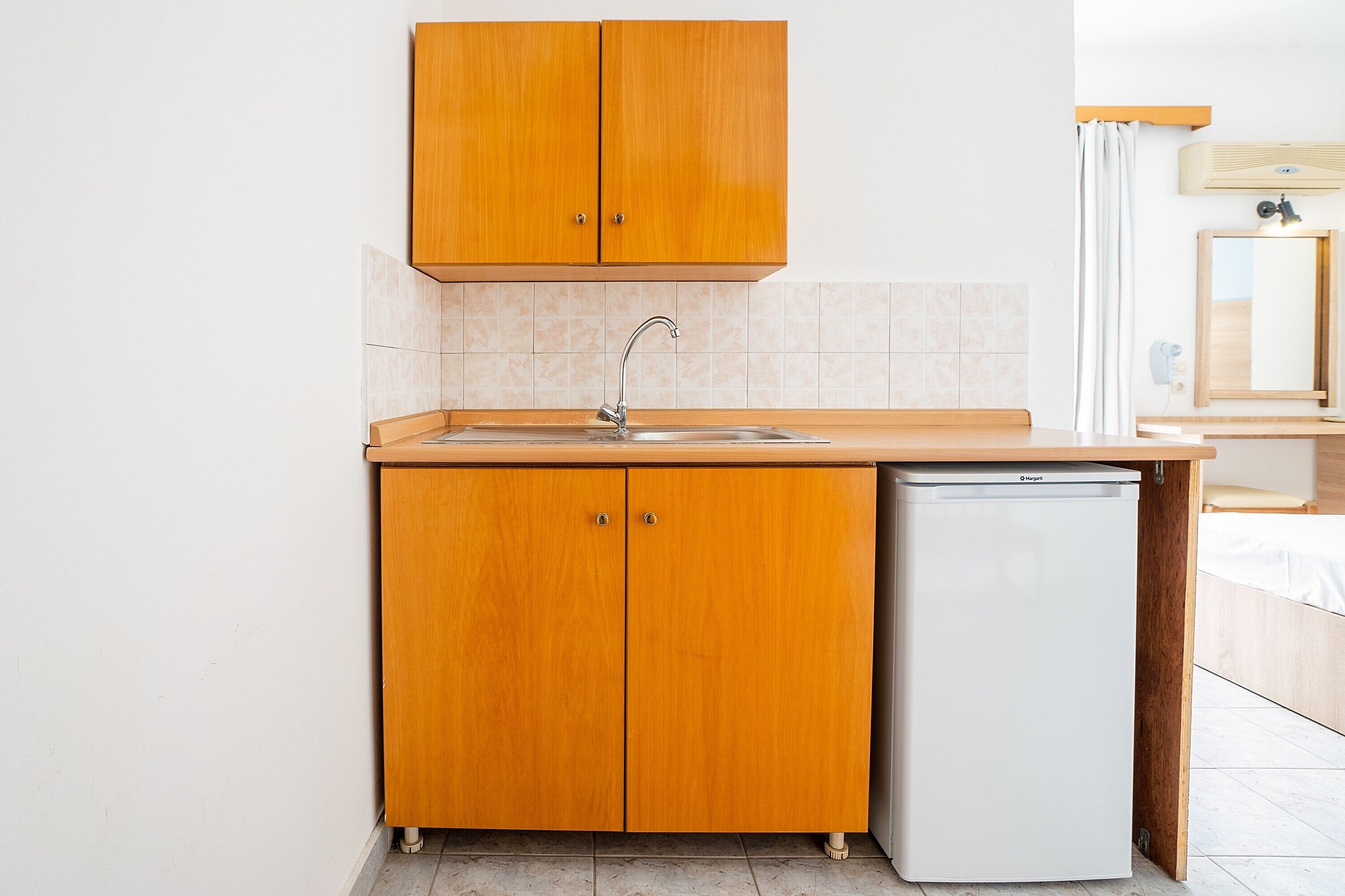 A compact kitchen with wooden cabinets, a sink, and a built-in dishwasher.