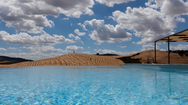 A swimming pool with clear blue water, surrounded by sand dunes and a clear sky. - Villa "Podere Spagliarda" with Private Pool, Terrace & Wi-Fi (San Quirico d'Orcia)