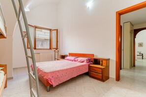A bedroom with a bed, nightstands, a wooden wardrobe, a ladder, and a mirror.