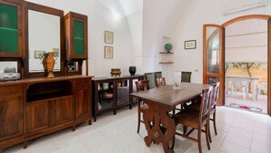 A dining area with a wooden table and chairs, a cabinet with glass doors, and a mirror. - Vacation Home "Villa Stella" with Private Terraces & Private Garden (alezio)