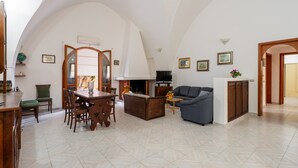 A spacious living area with a dining table, chairs, a sofa, and a fireplace. - Vacation Home "Villa Stella" with Private Terraces & Private Garden (alezio)