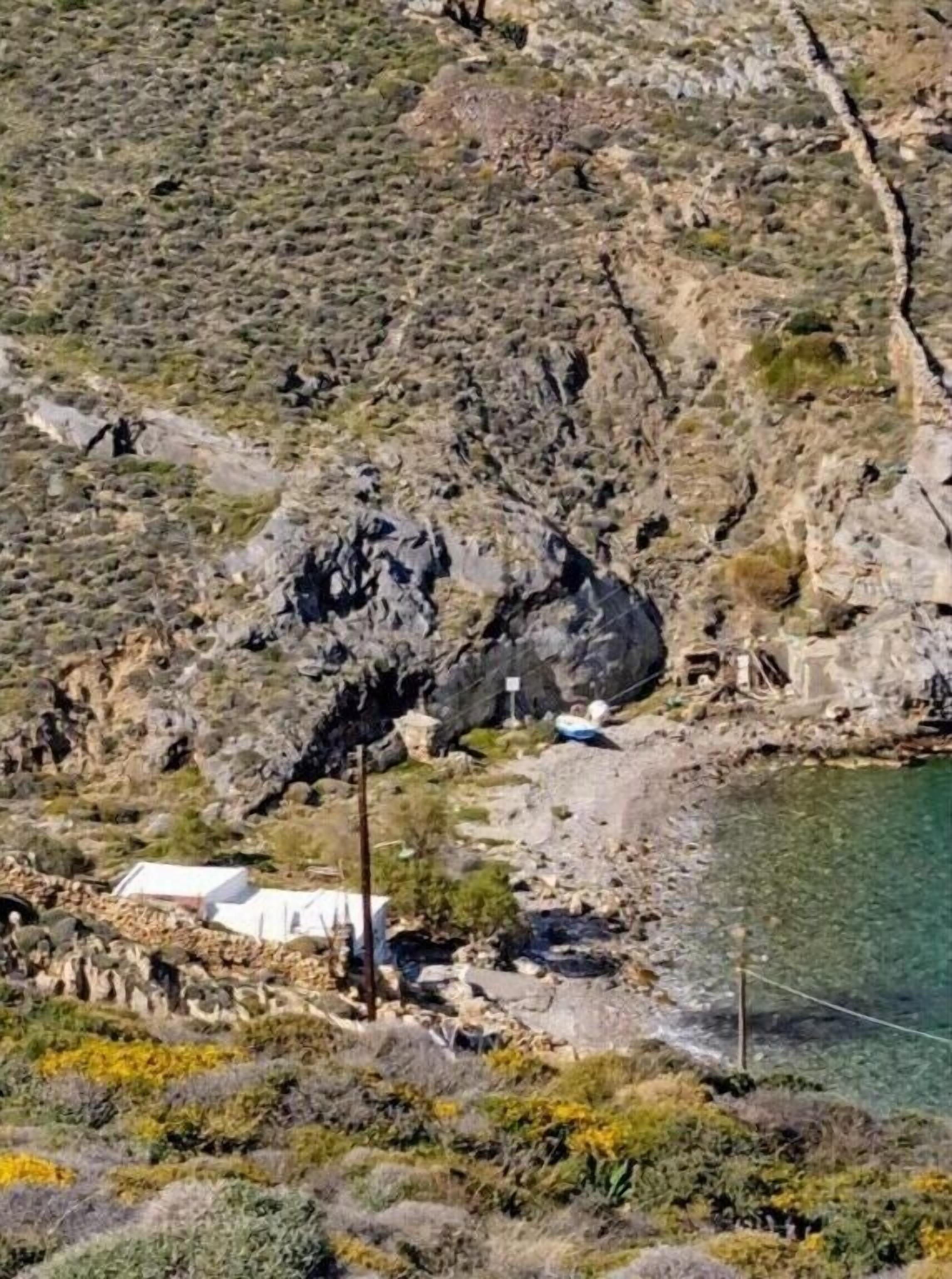 A rocky landscape with a small white building near a body of water.