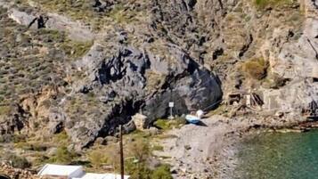 A rocky landscape with a small white building near a body of water.