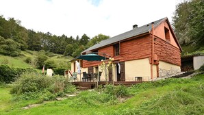 Een houten huis met een veranda, buitenmeubels en een trap die naar de ingang leidt.