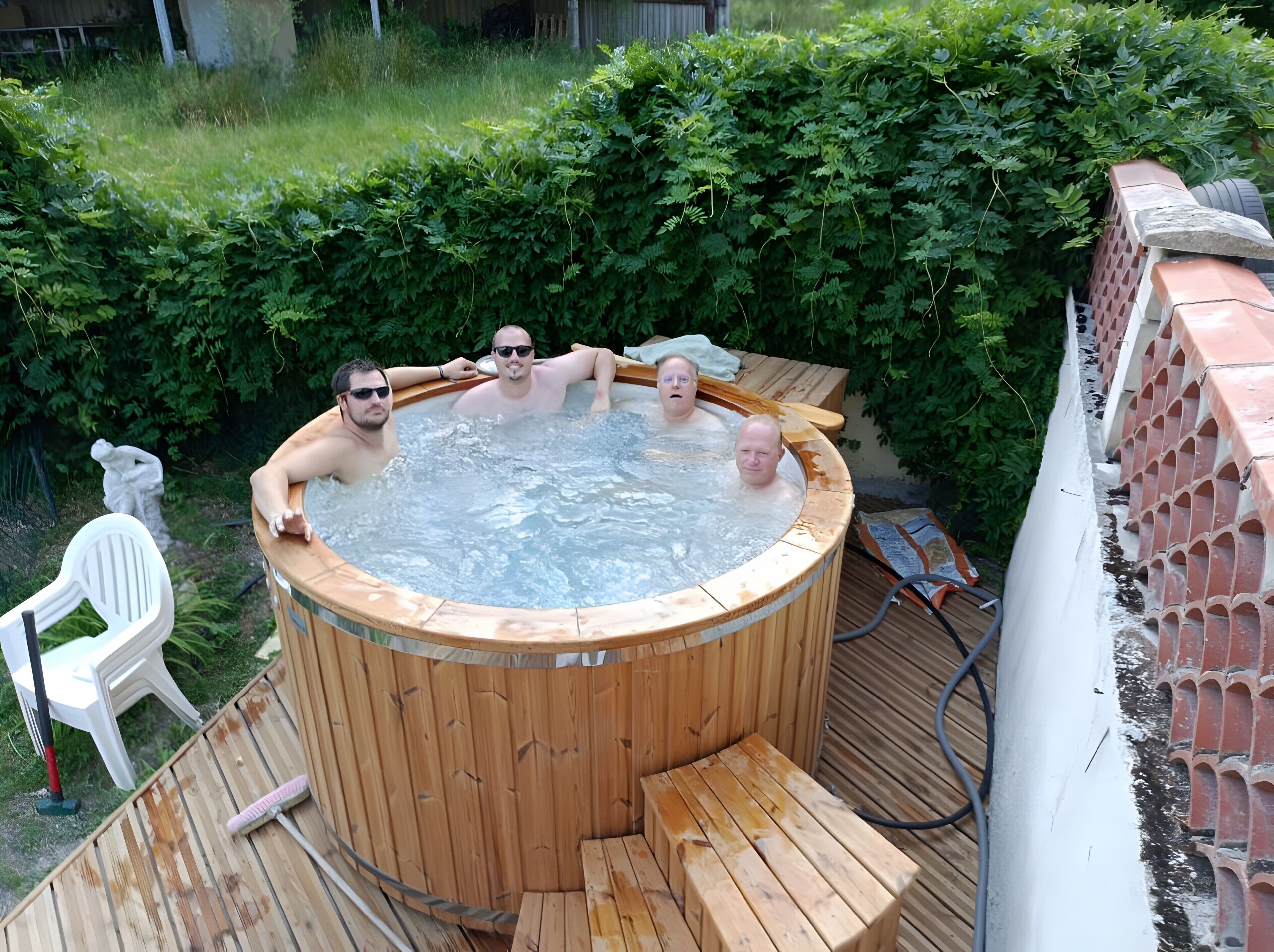 A hot tub with three people, surrounded by greenery and a wooden deck.