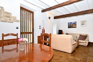 Ein Zimmer mit einem Holzesstisch, einem beige farbenen Sofa und einer Steinwand.