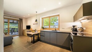 A modern kitchen with a large island, a dining area with a table and chairs, and a sliding glass door leading to an outdoor patio.