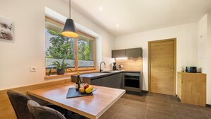A modern kitchen with a wooden countertop, a built-in oven, and a window with a view of trees.