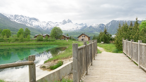 Un muelle de madera que conduce a una casa con vista a la montaña.