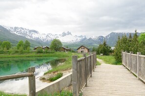 Une promenade en bois mène à une maison qui se trouve au pied d’une montagne.