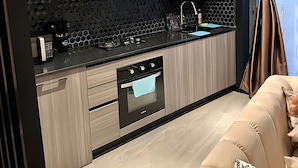 Een moderne keuken met donkere kastjes, een zwart aanrecht en een ingebouwde oven.