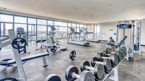 Een fitnessruimte met cardioapparatuur, gewichten en dumbbells.