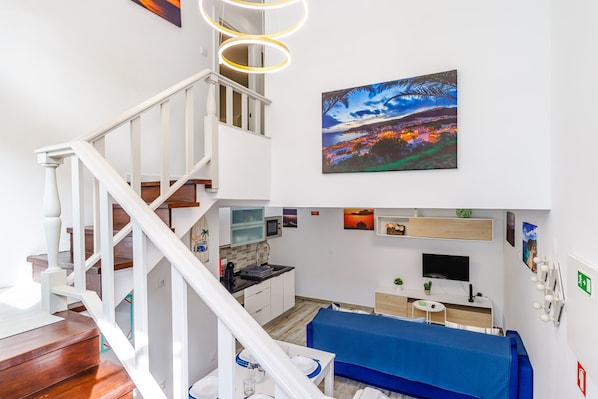 Un intérieur moderne comprenant un escalier, un coin repas, une cuisine et un espace de vie.