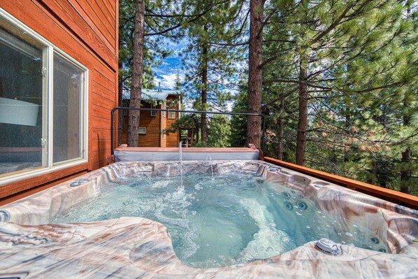 A hot tub with a marble interior, surrounded by trees and a wooden deck. - Bear Peak by Tahoe Getaways - 3BR Pet-Friendly w Hot Tub, EV Charger & HOA (Truckee)