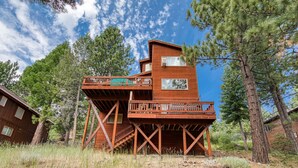 Une cabane en bois dotée d’une terrasse et d’un escalier, entourée d’arbres.