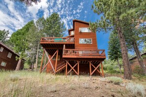 A wooden cabin with a deck and stairs, surrounded by trees. - Bear Peak by Tahoe Getaways - 3BR Pet-Friendly w Hot Tub, EV Charger & HOA (Truckee)