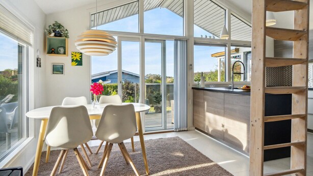 A bright kitchen with large windows, a dining area with white chairs, and a wooden ladder. - Nice home in Kerteminde with WiFi (Kerteminde)