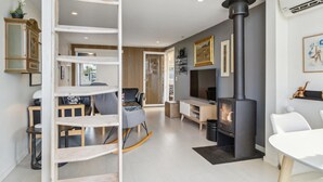 A modern living room with a fireplace, a dining area, and a seating space with a rocking chair. - Nice home in Kerteminde with WiFi (Kerteminde)