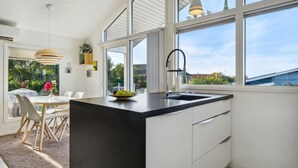 A modern kitchen with a black countertop, white cabinets, and a large window offering a view of the outdoors. - Nice home in Kerteminde with WiFi (Kerteminde)