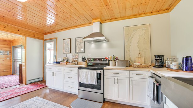Eine moderne Küche mit Holzboden, Edelstahlgeräten, weißen Schränken und einem roten Teppich.