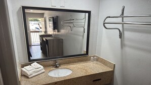 A bathroom with a granite countertop, a sink, a mirror, and a towel rack. - Budget Inn Express (Columbia)