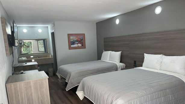 A hotel room with two beds, a wooden dresser, a vanity with a mirror, and a painting on the wall. - Budget Inn Express (Columbia)