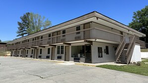 A two-story motel with a flat roof, multiple balconies, and a central entrance with a staircase. - Budget Inn Express (Columbia)