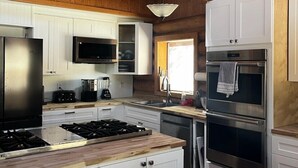 Une cuisine moderne avec des poutres en bois, des appareils en acier inoxydable et des meubles blancs.
