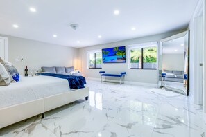 Una camera da letto moderna con un letto grande, una panca e una TV appesa al muro.