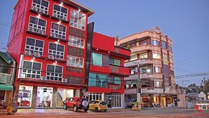 A multi-story hotel with a red facade, multiple balconies, and a visible restaurant named "Universal Bed & Breakfast". - Sabel Travelers Inn (Laoag)