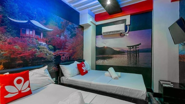 A hotel room with a bed, a red pillow, a wall mural, and an air conditioning unit. - Sabel Travelers Inn (Laoag)