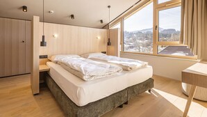 Quarto moderno com cama grande, guarda-roupa de madeira e escrivaninha.