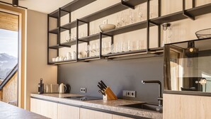 Cozinha moderna com bancada de mármore, prateleiras embutidas com copos e o logotipo da Bosch.