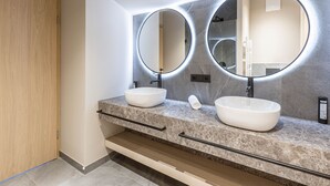 Ein modernes Badezimmer mit zwei Waschbecken, einem großen Spiegel und einem Handtuchspender.