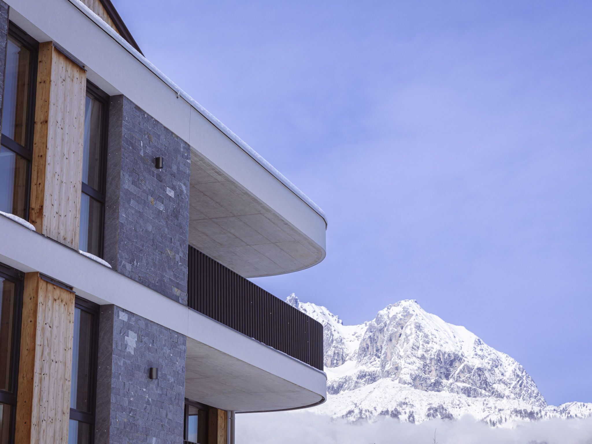 Ein modernes Gebäude mit einem Balkon mit Blick auf einen verschneiten Berg.