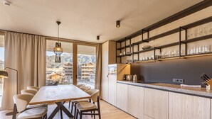 A modern kitchen with a large island, wooden cabinets, and a view of a mountain landscape. - Premium mit 2 Schlafzimmer by Interhome (Oberndorf in Tirol)