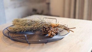 A clear view of a room with a wooden table displaying a decorative arrangement of pine branches and pine cones.