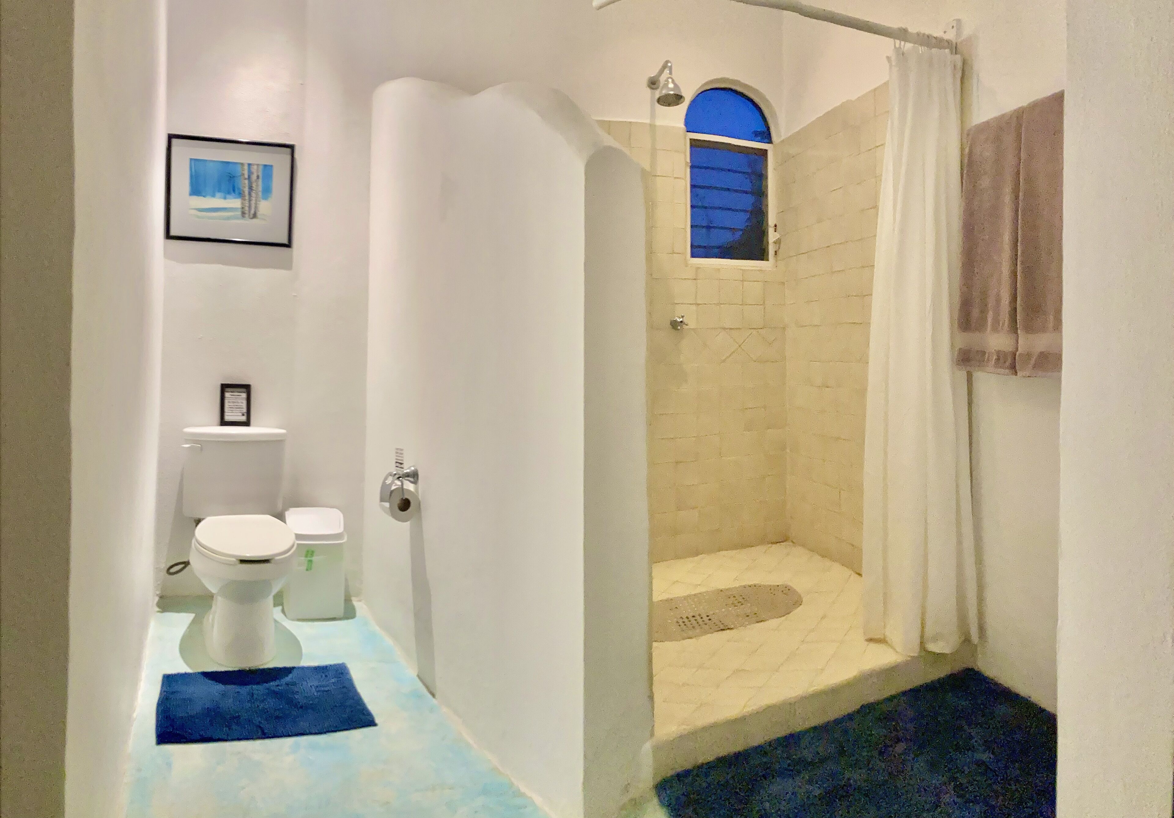 Une salle de bain comprenant des toilettes, un bidet, une douche et une petite fenêtre.
