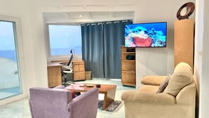 Un salon moderne avec un canapé, un fauteuil et un téléviseur.