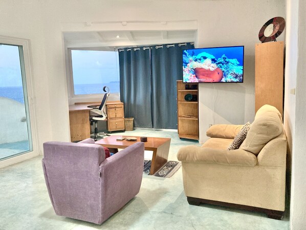 A modern living room with a sofa, armchair, and TV. - Casa Lamanai (Punta de Mita)
