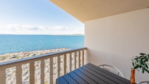 Een balkon met uitzicht op zee, een tafel en een stoel.