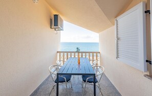 A balcony with a table and chairs, overlooking the sea. - Beach front apartment in Kosljun with WiFi (Kosljun)
